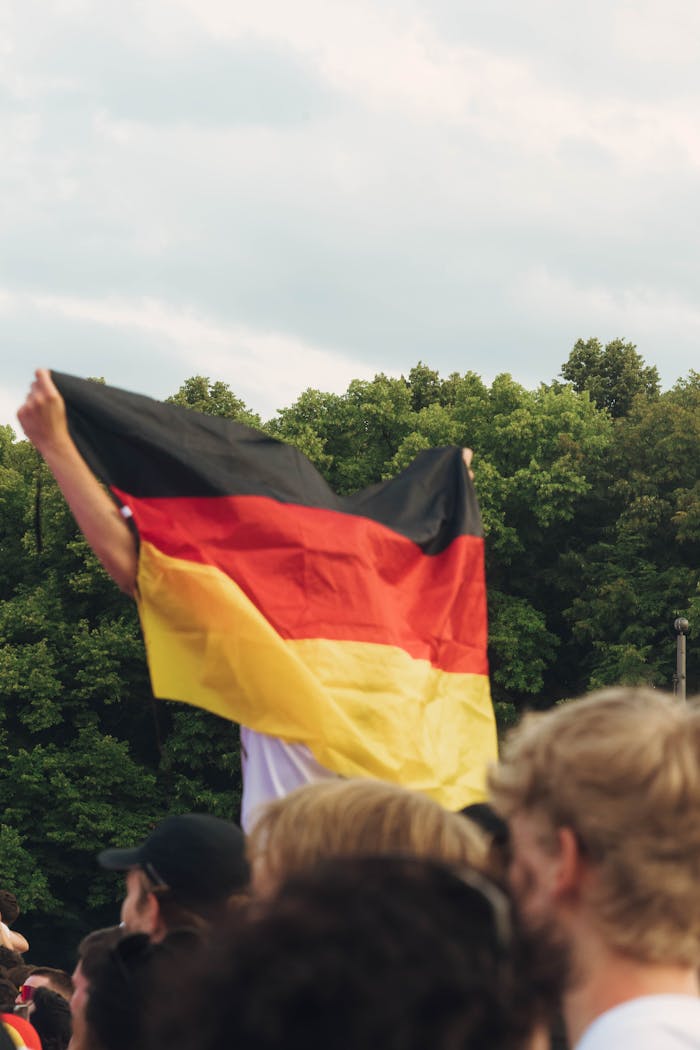 Crowd celebrating with a German flag at an outdoor gathering in Berlin.